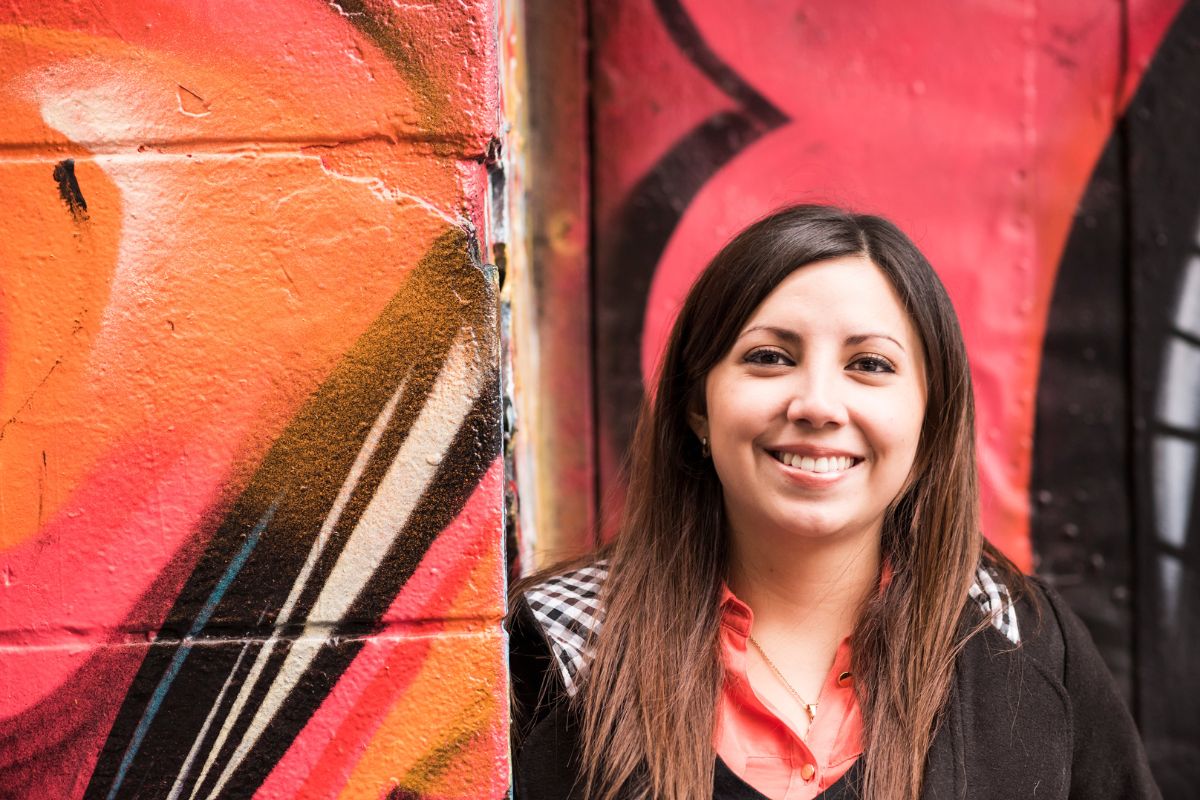 Student standing in front of graffiti wall outdoors