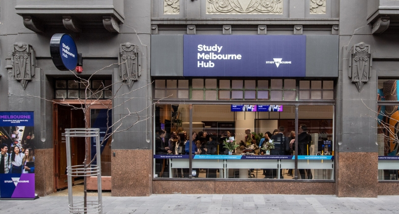 Outside of the Study Melbourne Hub building with branding and Study Melbourne logo, people at an event inside and banner out the front, banner says Melbourne Australia's best student city since 2015