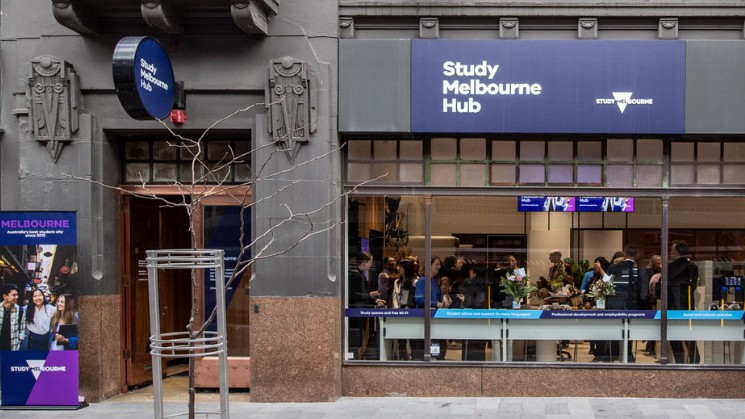 Outside of the Study Melbourne Hub building with branding and Study Melbourne logo, people at an event inside and banner out the front, banner says Melbourne Australia's best student city since 2015, Study Melbourne logo