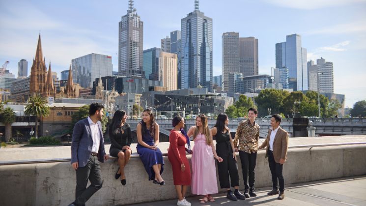 Students on the banks of the Yarra river at Southbank with Melbourne city in the background