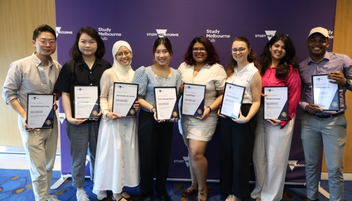 2024 Ambassadors with awards in front of Study Melbourne hub branding