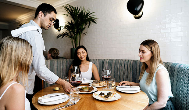 Waiter serving brunch to three women