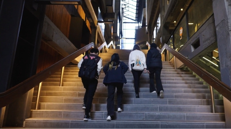 Four students at university walking up concrete staircase