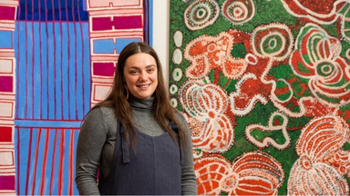 Taylah standing in front of enormous colourful first nations artwork