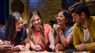 Friends at an outdoor cafe with pizza, taking photos of food