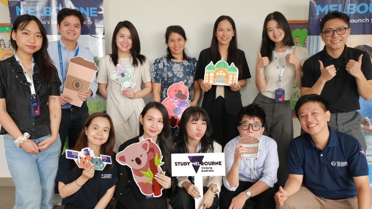  Study Melbourne Hub Ho Chi Minh City and Victorian Government Trade and Investment Office members group photo, people holding cardboard cut out coffee cups, koalas, wombats, Flinder's Street Station and sign with Study Melbourne, Victoria, Australia logo