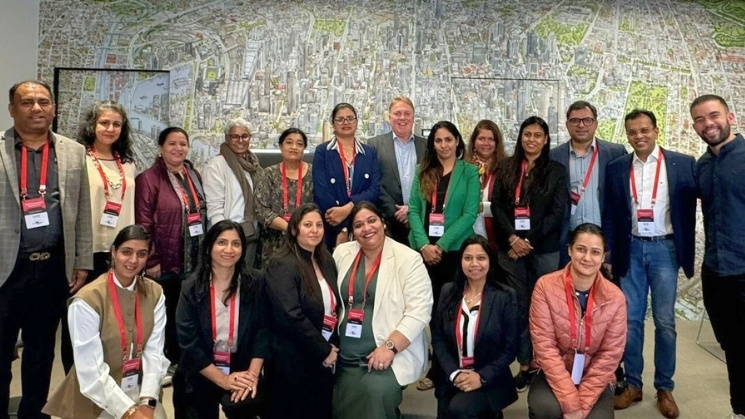 Group of delegates at the Study Melbourne hub in front of a wall with a map of Melbourne in the background