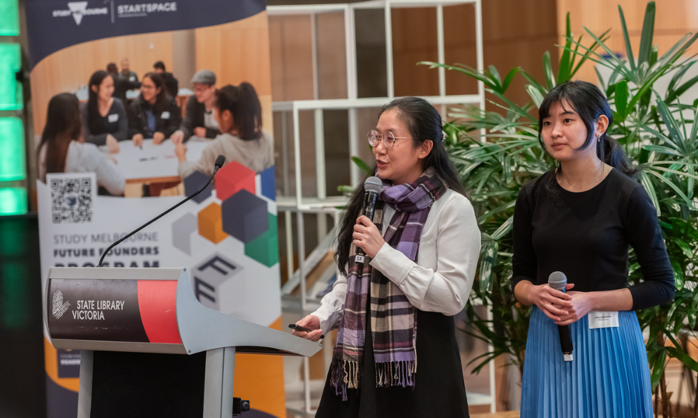 Photograph of two women presenting at a podium labeled 