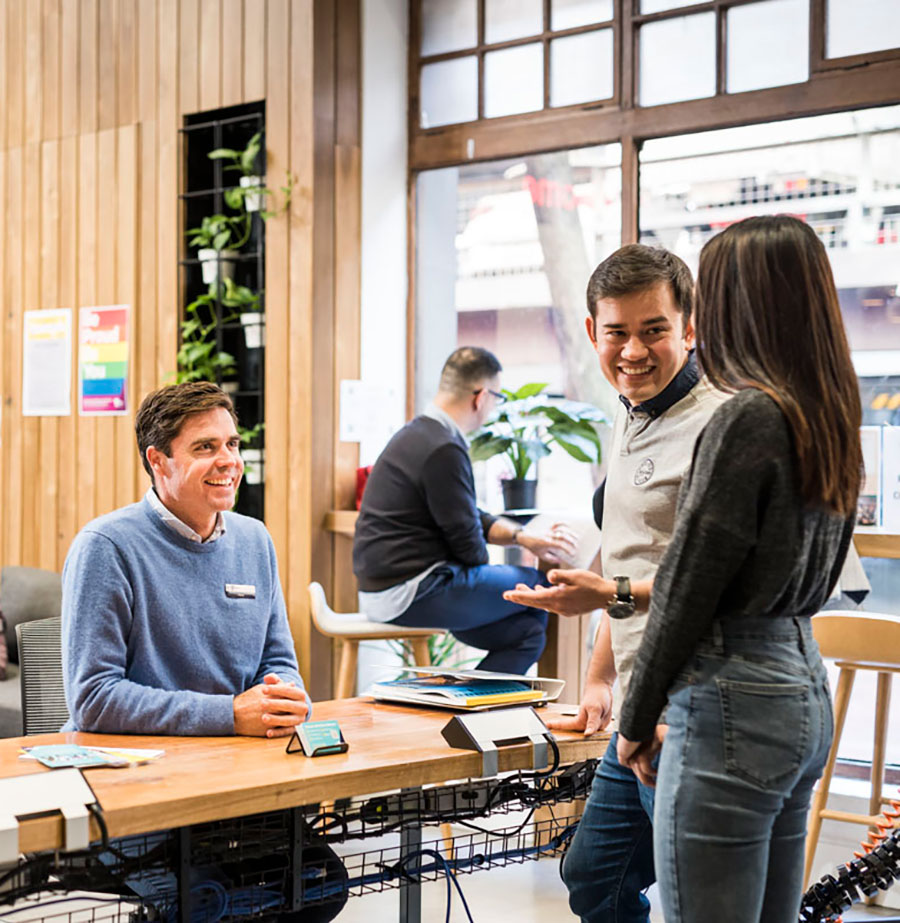 Two students chatting to staff in Hub