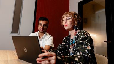 Student working with mentor on laptop