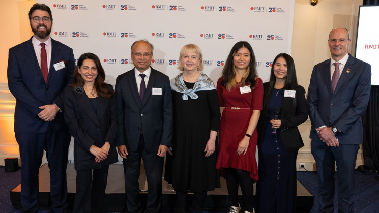 A group of people posing in front of an RMIT backdrop.