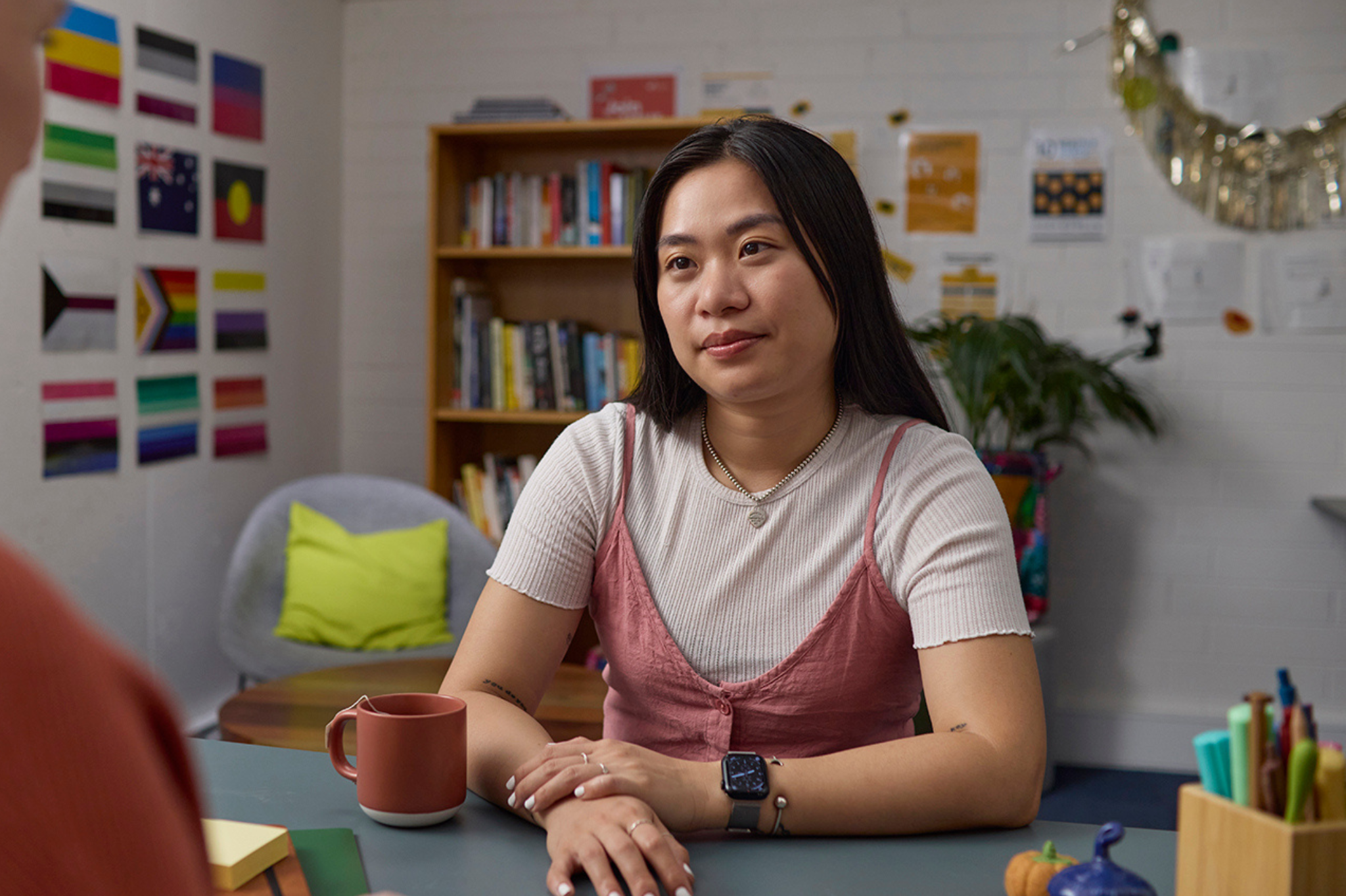Photograph of a person sitting at a desk in a room. 