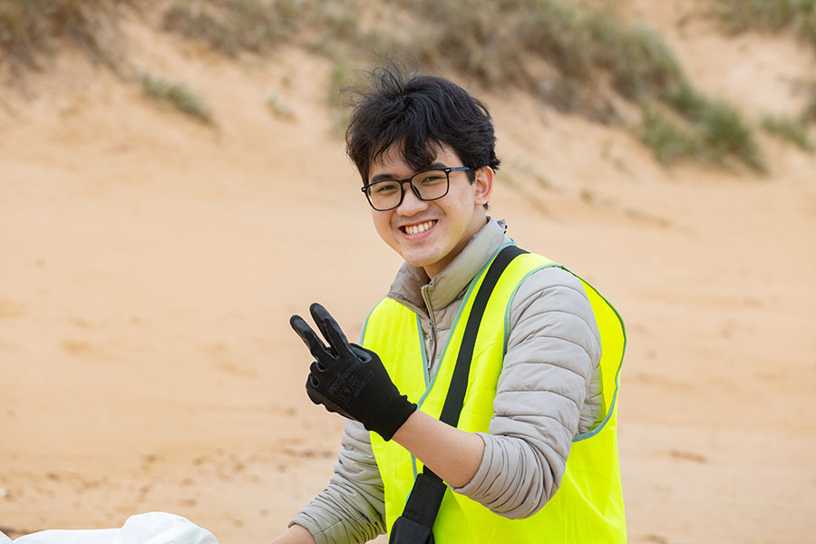 Student on beach in high vis