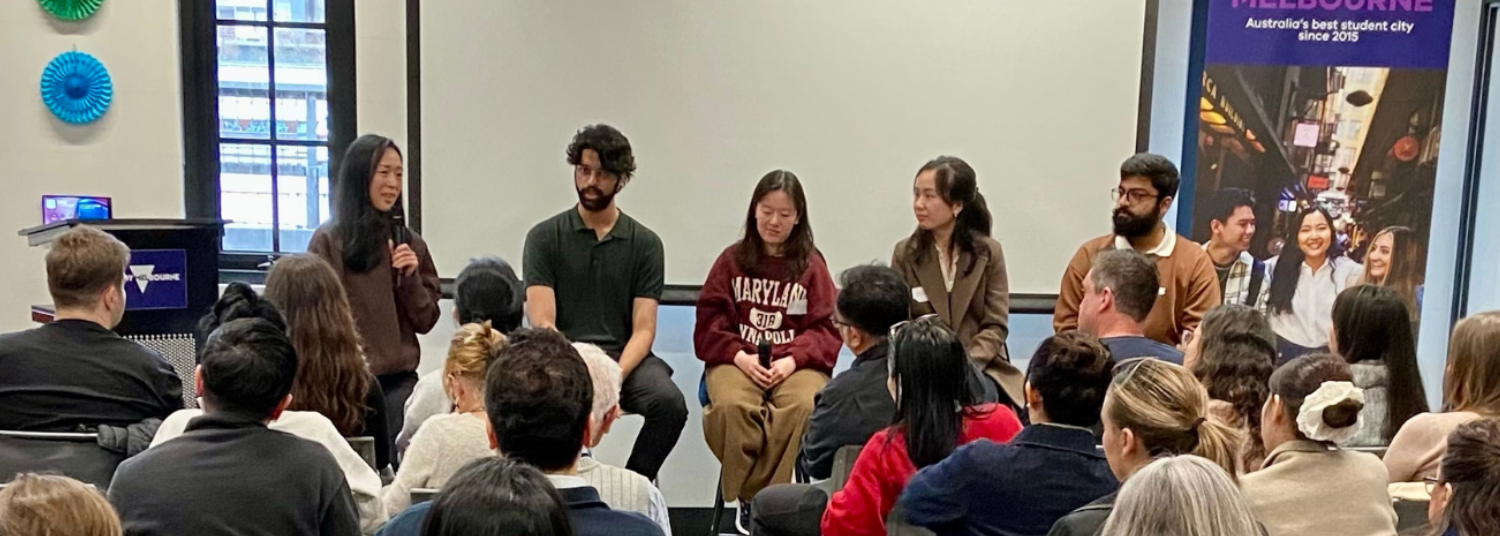 Group photograph of diverse adults seated in front of a large audience