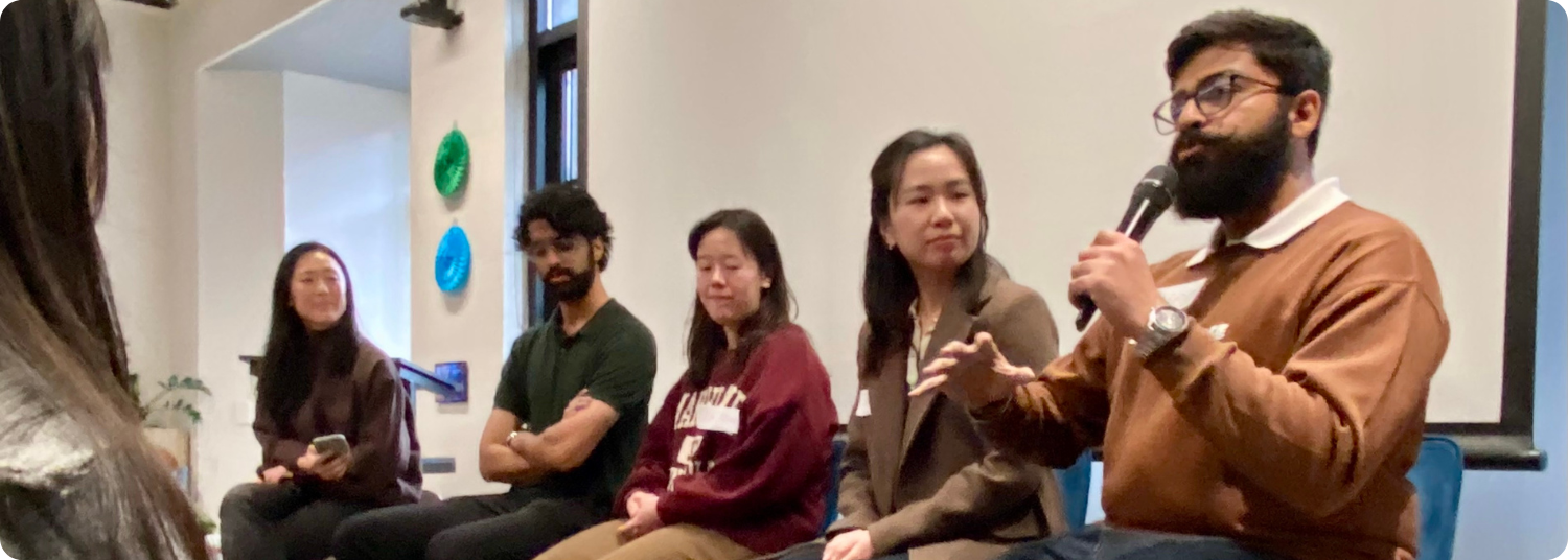 Group photograph of diverse adults seated and one person is holding a mic