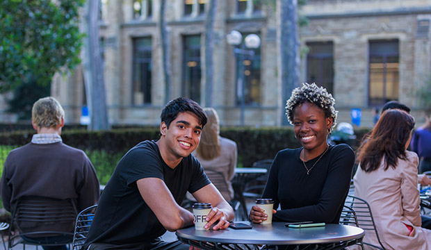 Two students sitting outside drinking coffee