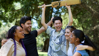 International students playing cricket in the gardnes