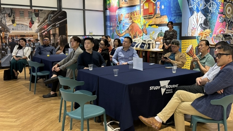 Alumni seated at tables for networking event at KL hub, Melbourne graffiti artwork in background