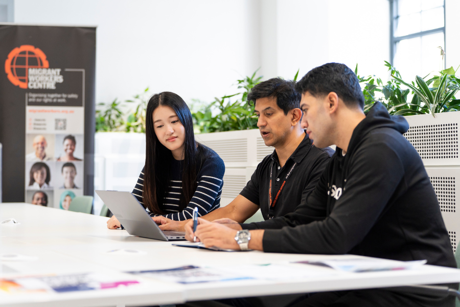 Three people working togetehr to use a laptop