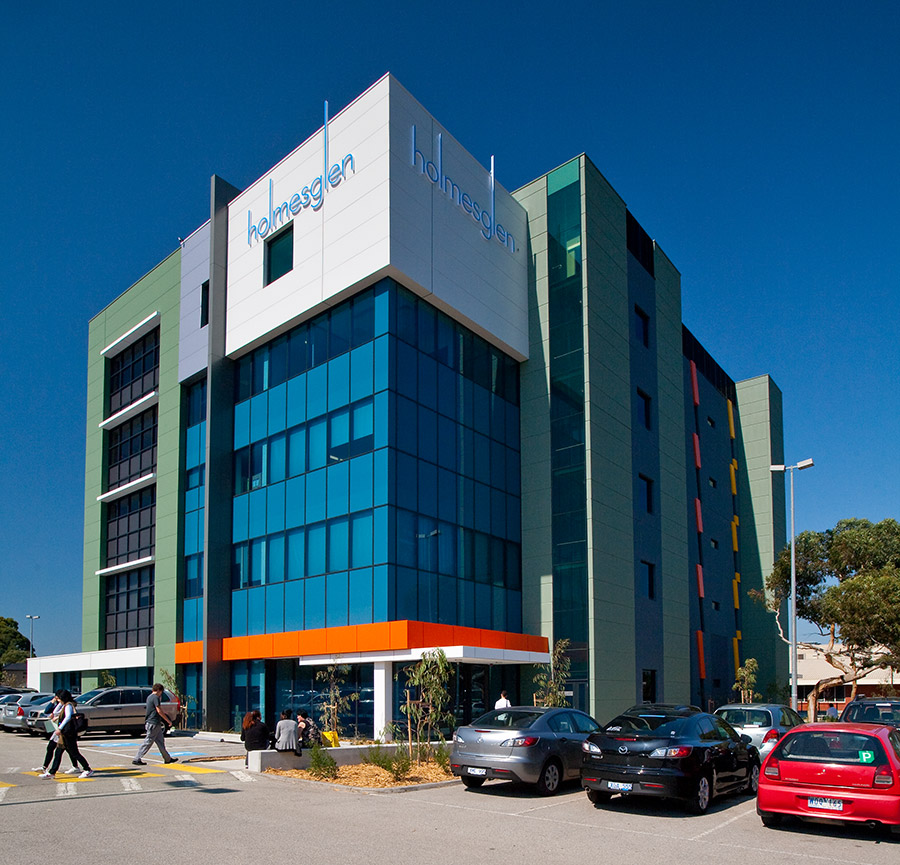 Midrise building with carpark and students walking to and from the campus