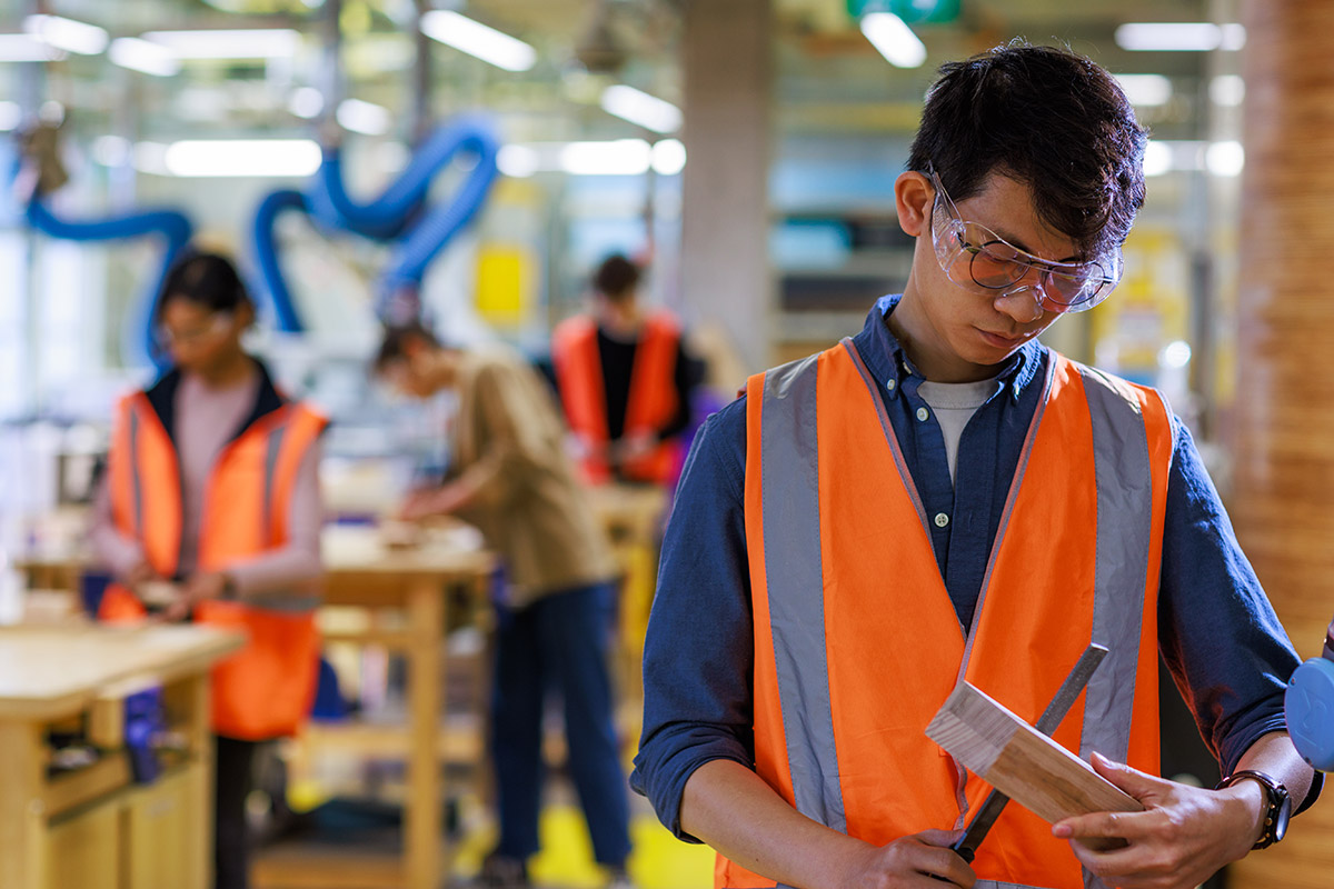 Students in high vis jackets doing wood work