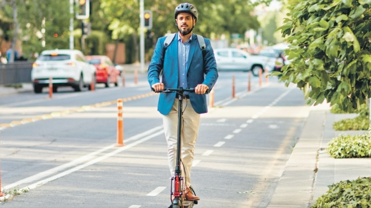 Student riding a scooter safely with a helmet on