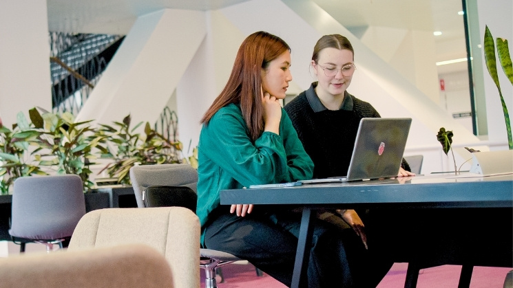 Two students working together on a laptop