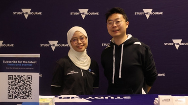 Two Study Melbourne Ambassadors at a booth, branding in background