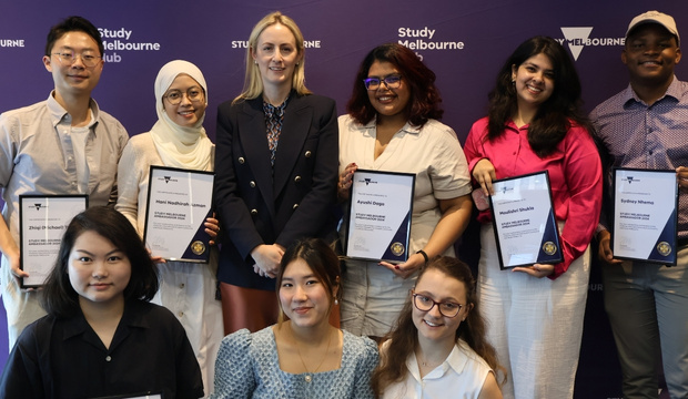 2024 Study Melbourne student ambassadors group photo holding awards with branding in background