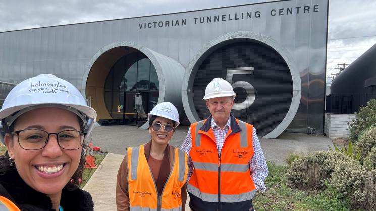 3 people in a high-vis vest standing in front of the Victorian Tunnelling Centre