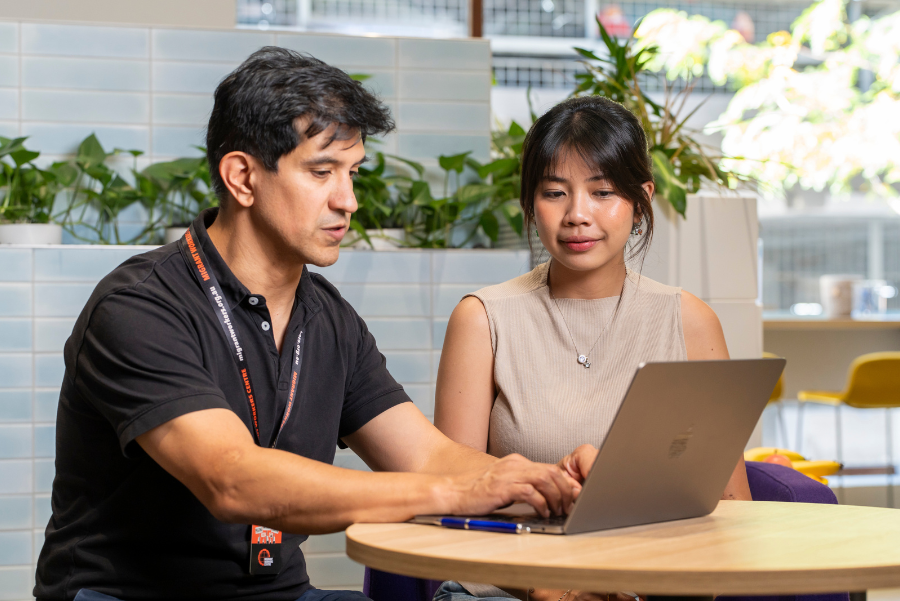Two people sitting together and looking at a laptop 