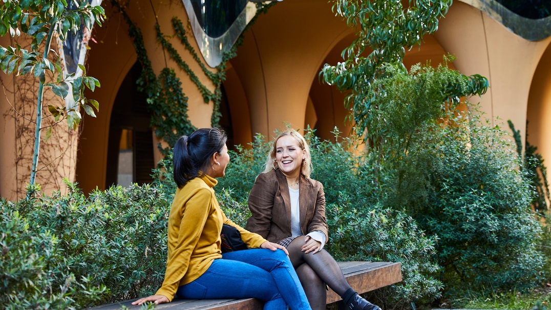 Students talking on a bench outside a university