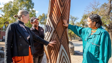 Educator showing students a carved artifact along the Yarra River