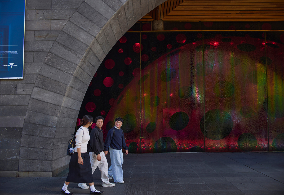 3 people walking in front of the NGV