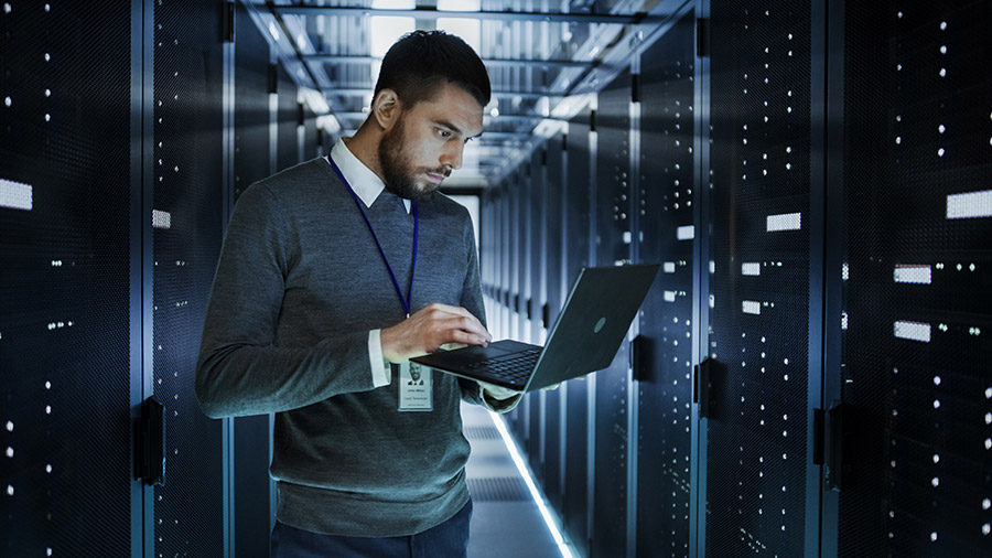 IT worker with laptop standing in server room