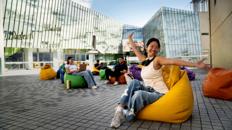 Students sitting on bean bags in front of campus