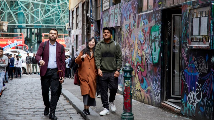 Three students enjoying graffiti artwork in Hosier Lane in Melbourne city