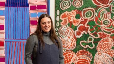 Artist Taylah Eid standing in front of large colourful abstract artwork