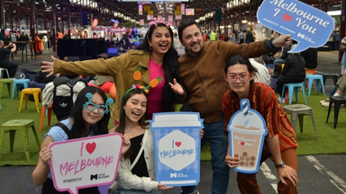 International students at the night market wearing fun summer themed accessories and holding I love Melbourne cut outs