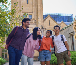 A group of students standing in front of a Melbourne University building, surrounded by greenery.